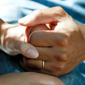 Manos entrelazadas durante una situación de acompañamiento y cuidado